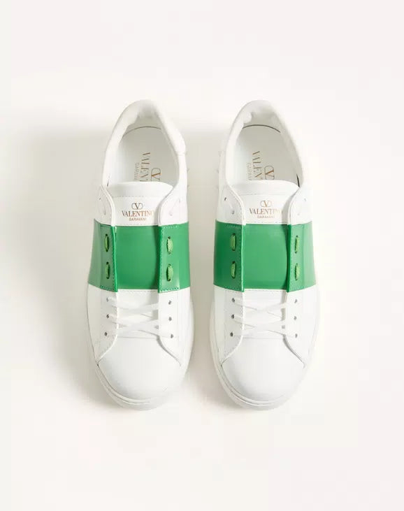 Pair of white sneakers with green back panels and white laces, padded tongue.