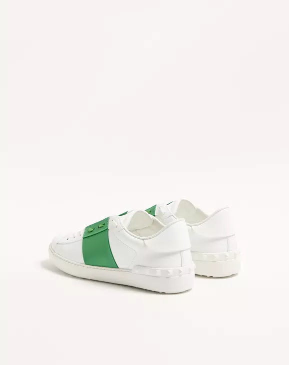 White open sneaker with green heel-side panel, lace-up, cushioned midsole.