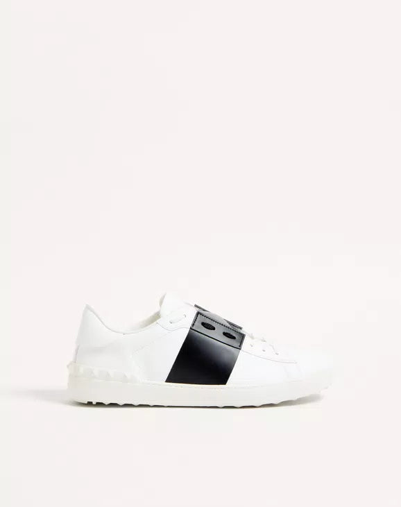 Calfskin open sneaker profile in white with black central strap panel and lace-up.