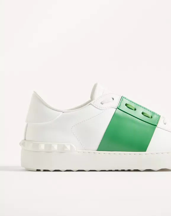 White leather sneaker with green strap detail, lace-up, textured rubber sole.