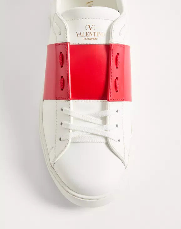 White open sneaker with red heel panel, white laces; Valentino Garavani logo tab.