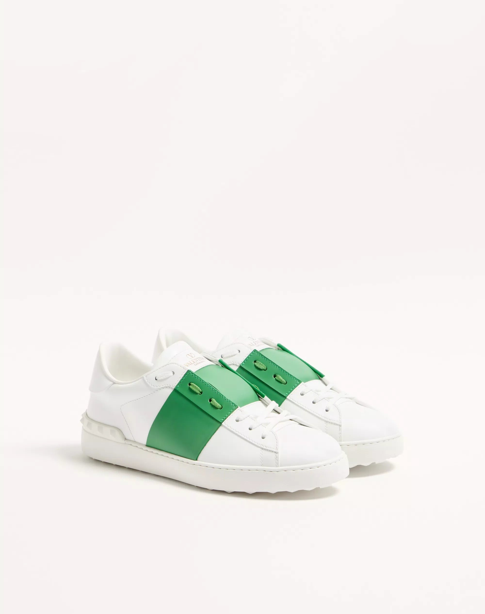 White open sneaker with green side panel, lace-up eyelets, low sole.