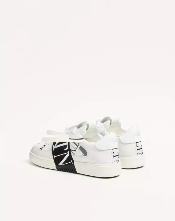 White low-top sneaker pair, showing black side band and rear logo detail