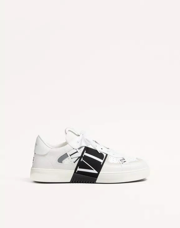 White low-top sneaker with black center band, side logo detail, lace-up design