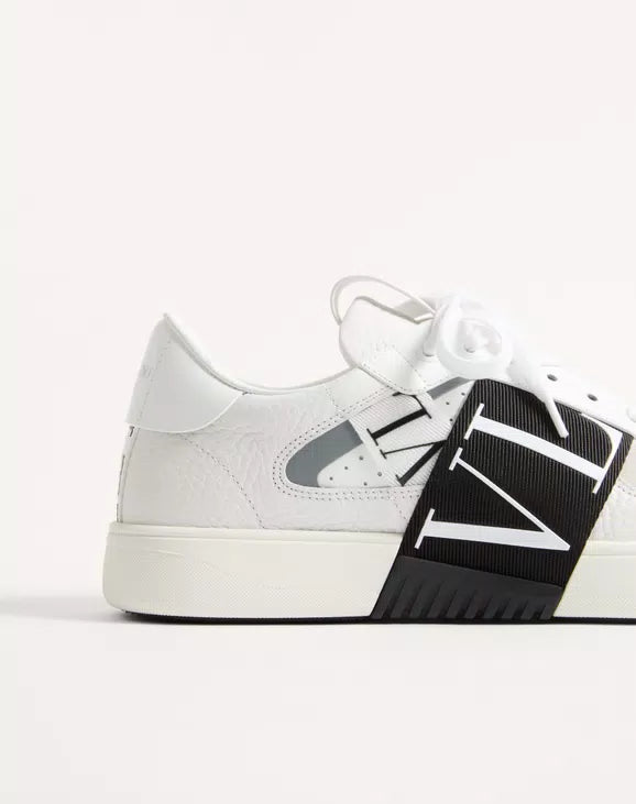 White low-top sneaker with oversized black panel and contrast logo band