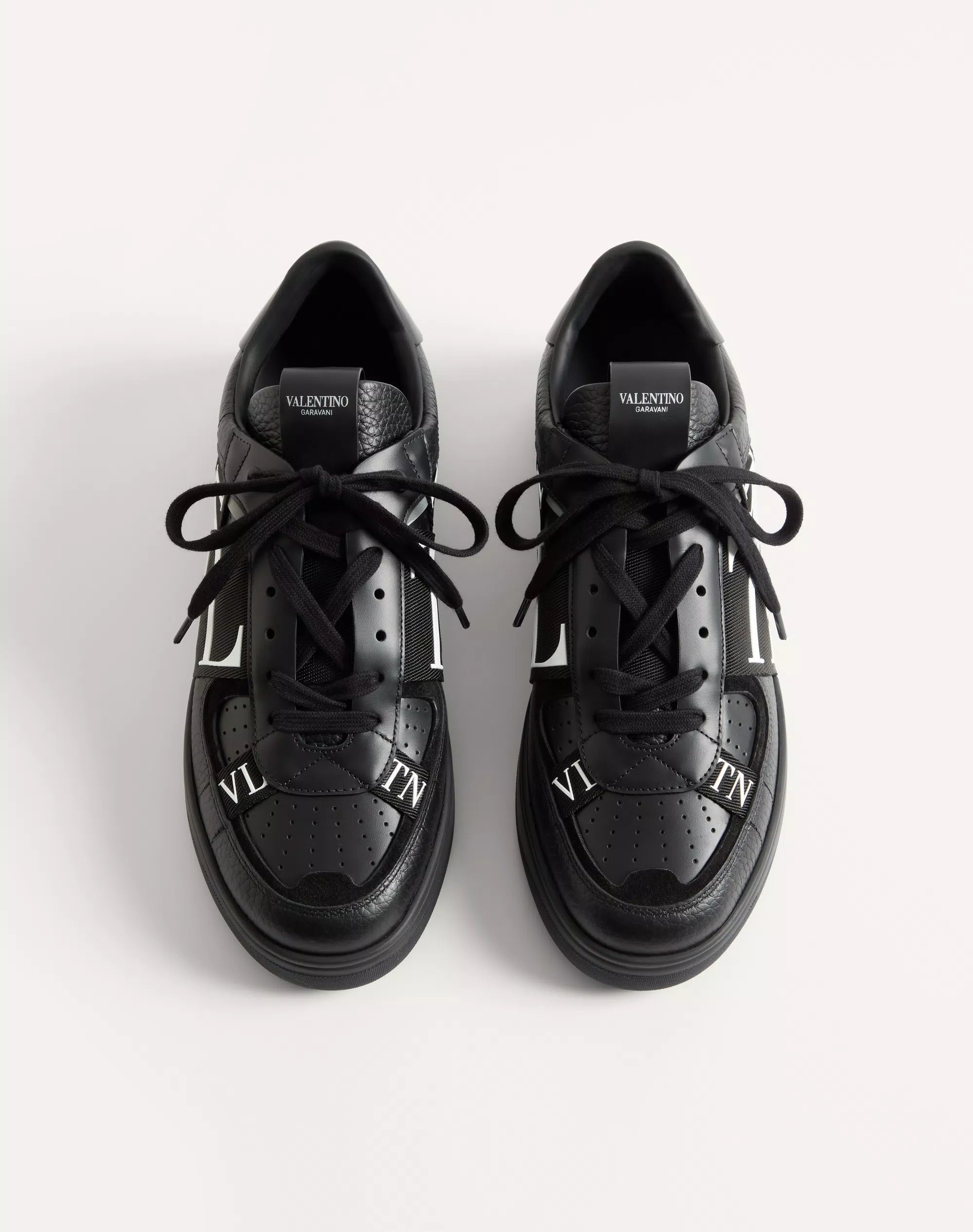 Black leather low-top sneaker pair with lace-up front and white VL7N logo bands