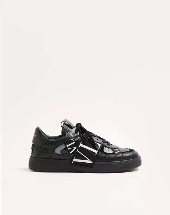 Black leather low-top sneaker side profile with white VL7N logo band and laces