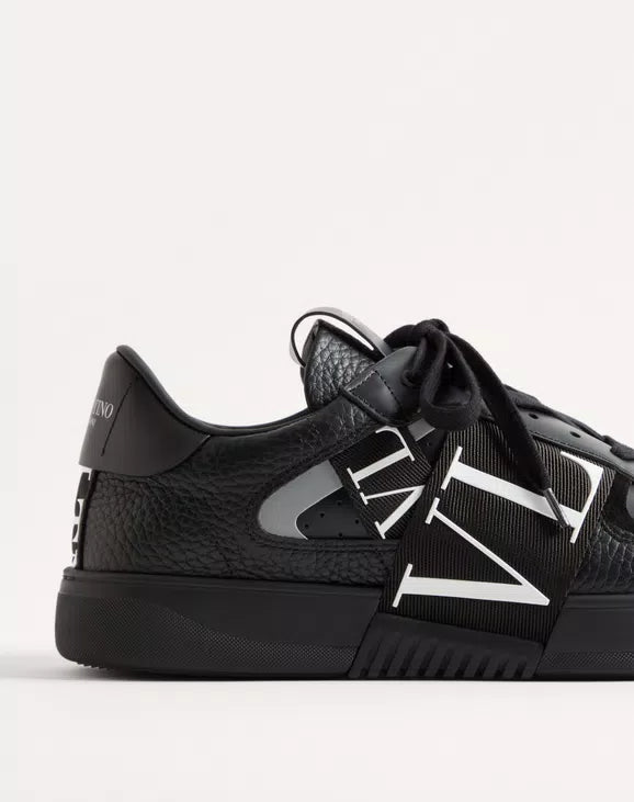 Black leather low-top sneaker side with bold white VL7N bands and lace