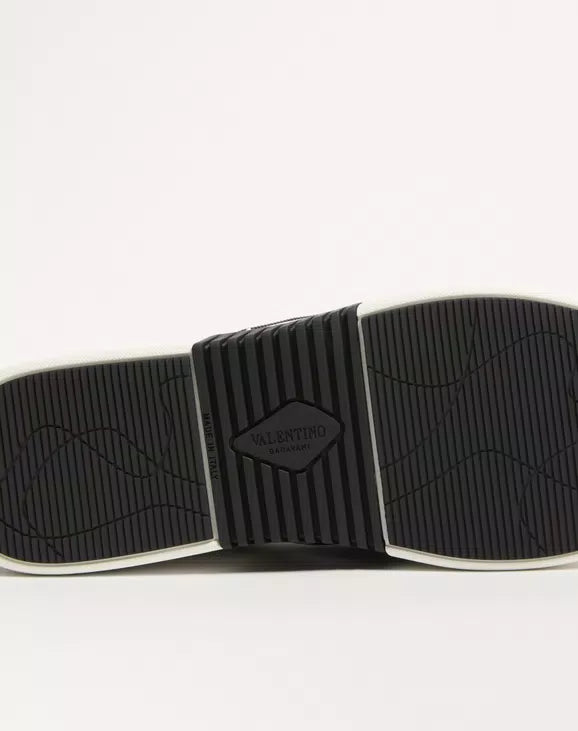 Black rubber outsole with tread and brand stamp on sneaker sole