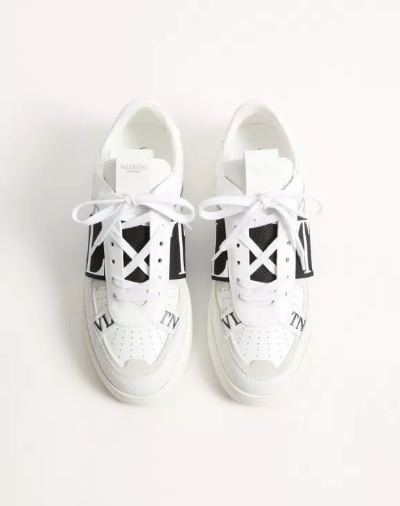 White low-top sneakers pair with black logo bands and white lace-up tops