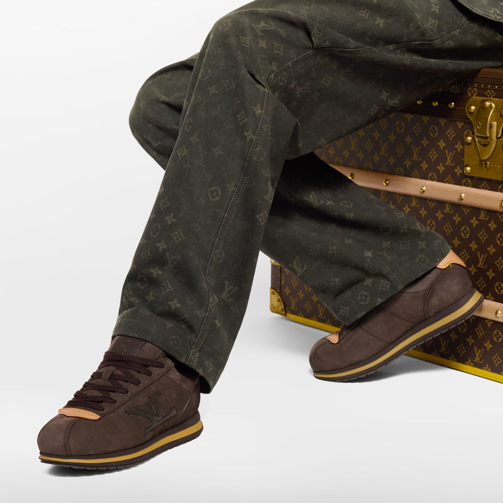 Dark brown LV BUTTERSOFT sneakers with tan laces and side LV logo, worn with jeans.