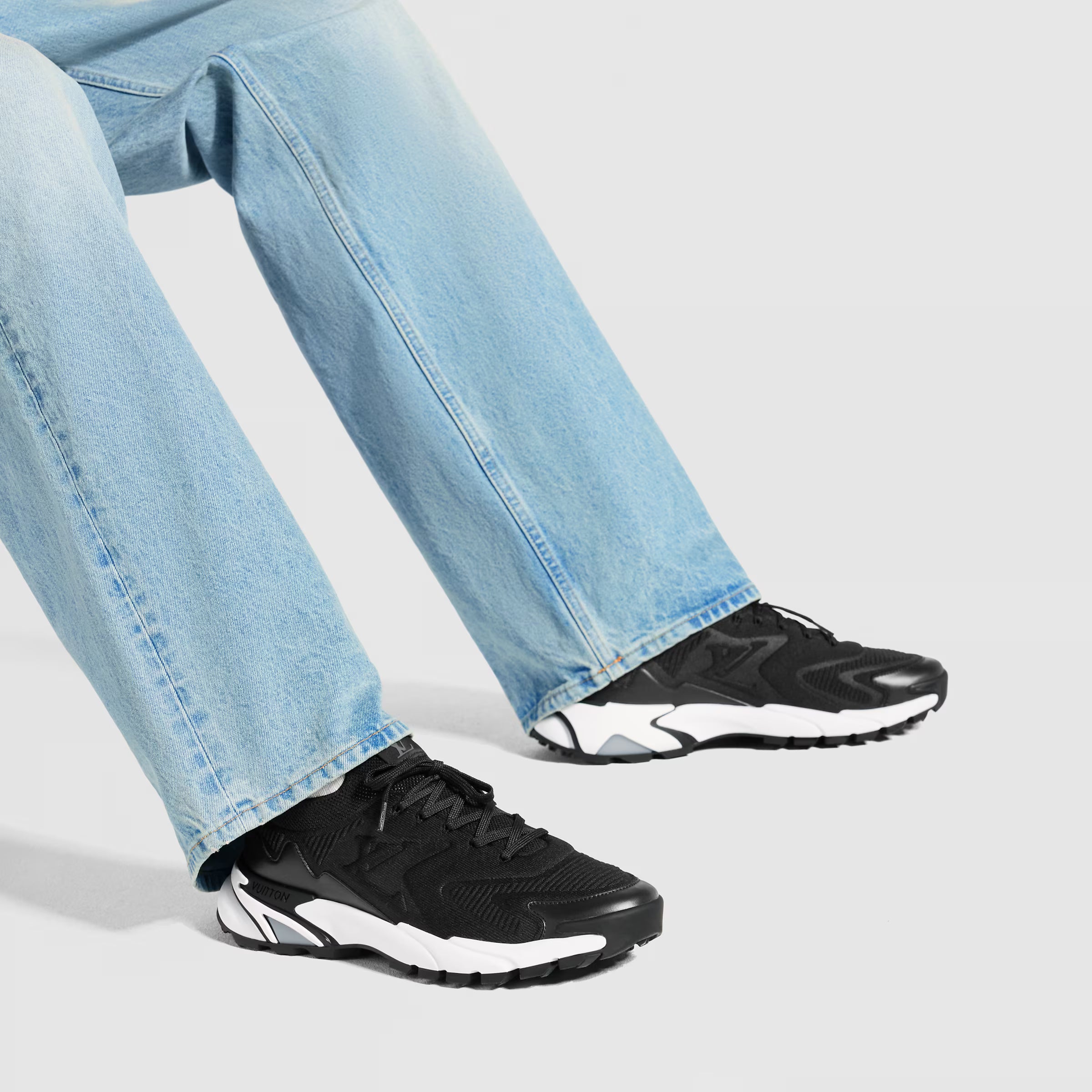 Black running sneakers with white midsoles worn with light blue jeans