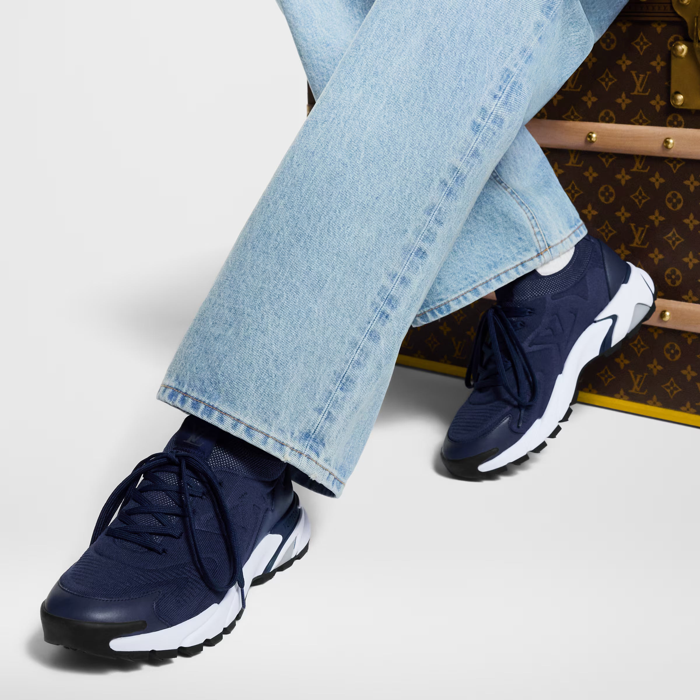 Louis Vuitton navy runner sneakers on feet with light blue jeans and white sole
