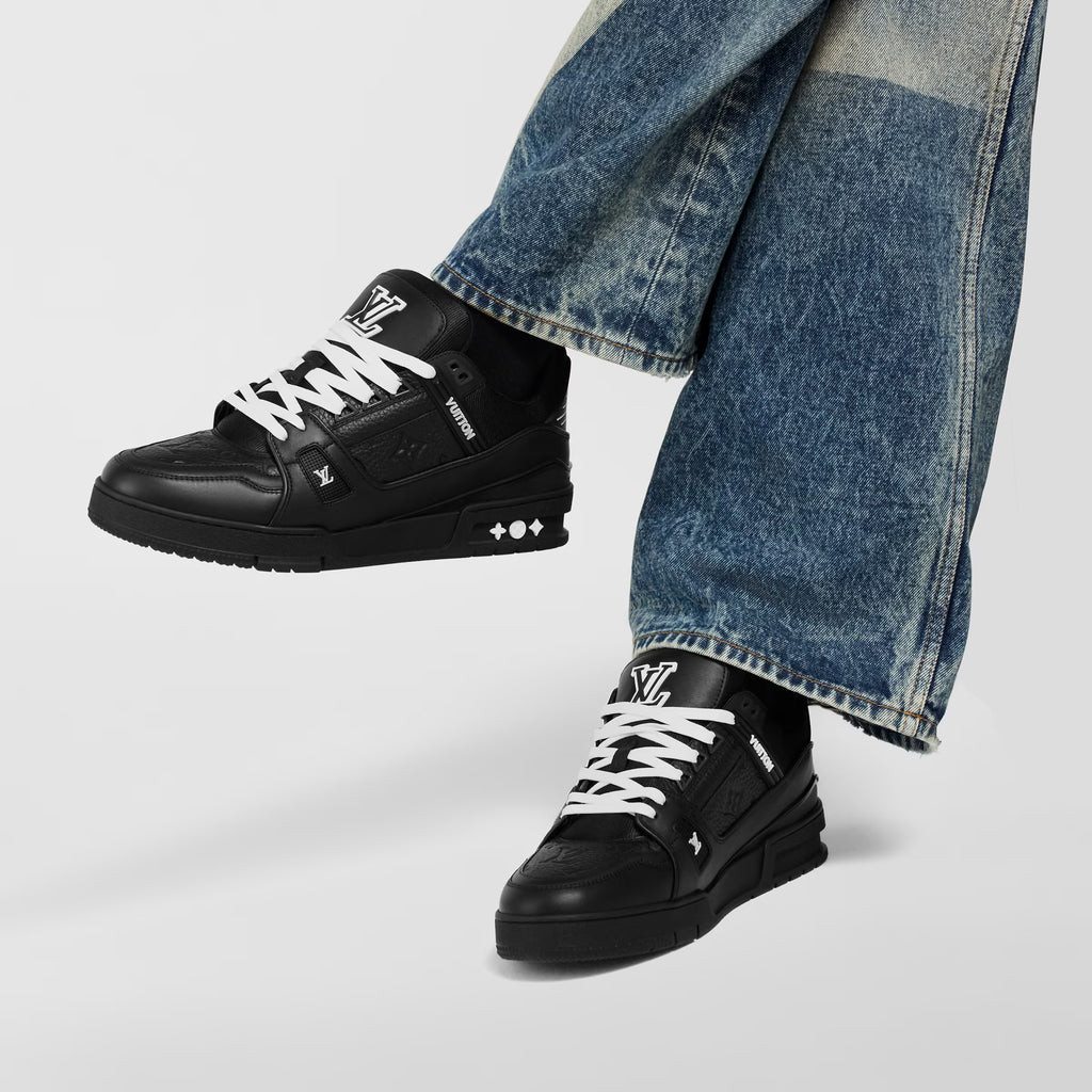 Black trainer sneakers on feet with blue jeans, white lace detail