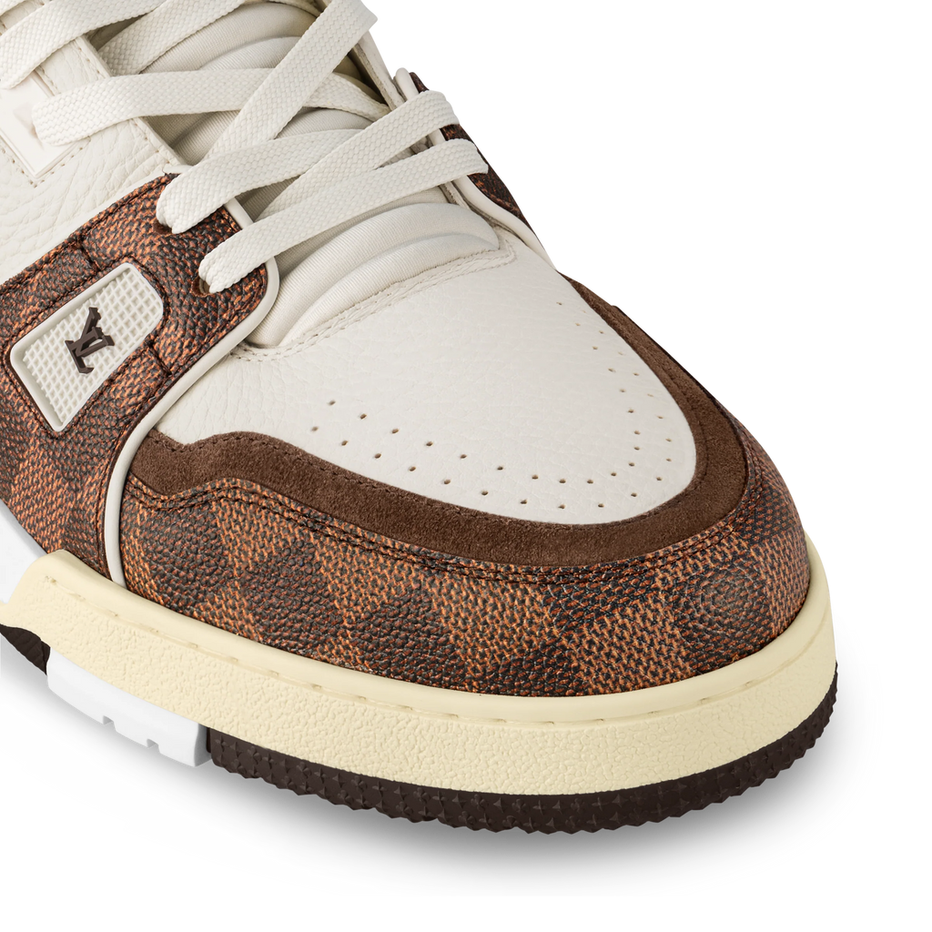 Close-up of white and brown sneakers with textured side panel and lace eyelets.