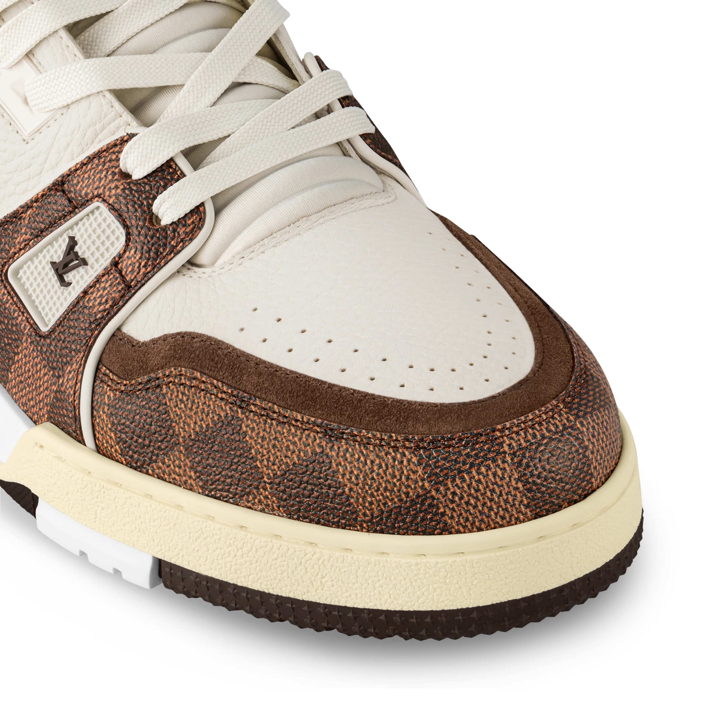 Close-up of white and brown sneakers with textured side panel and lace eyelets.