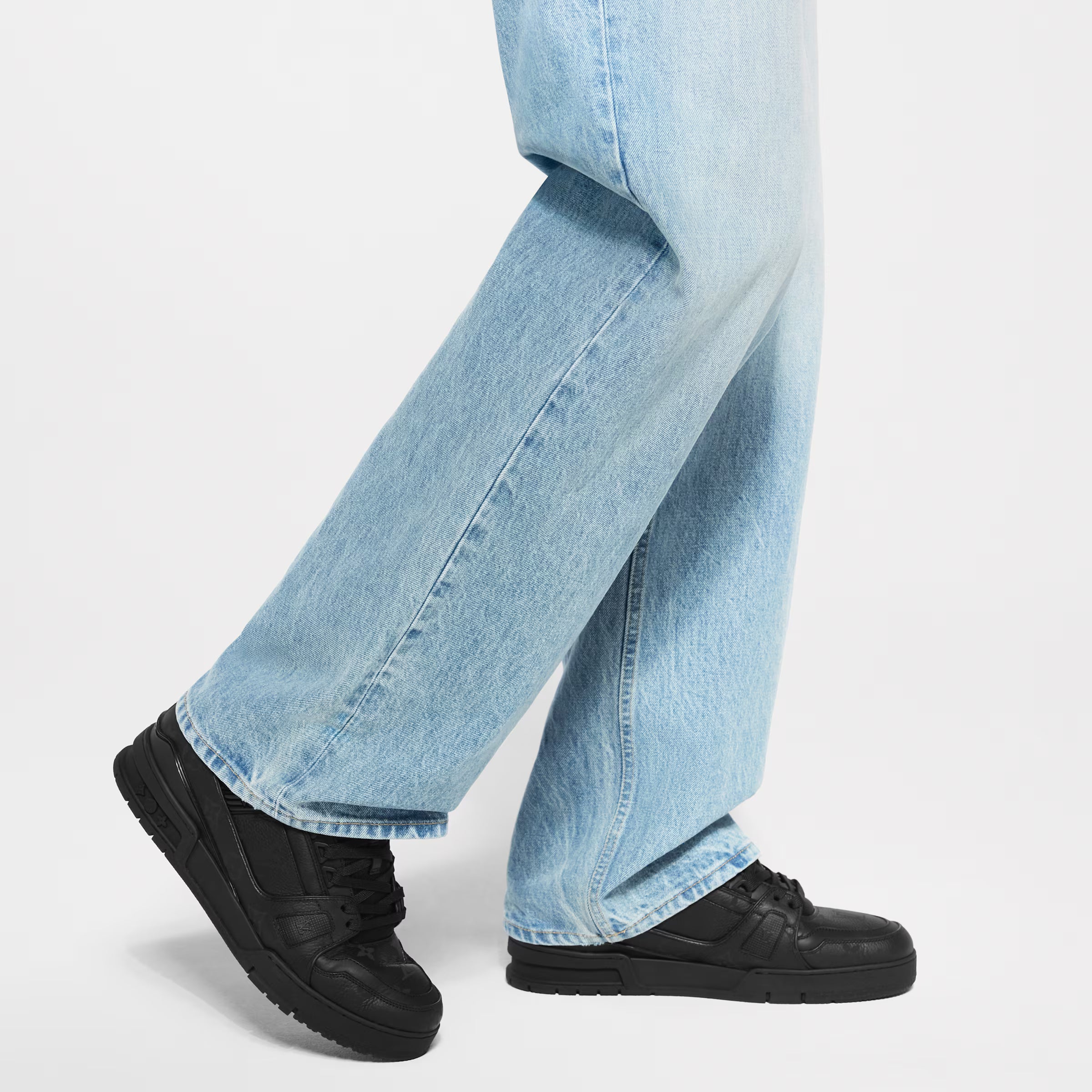 Black LV Trainer sneakers worn with light blue jeans, lace-up low tops