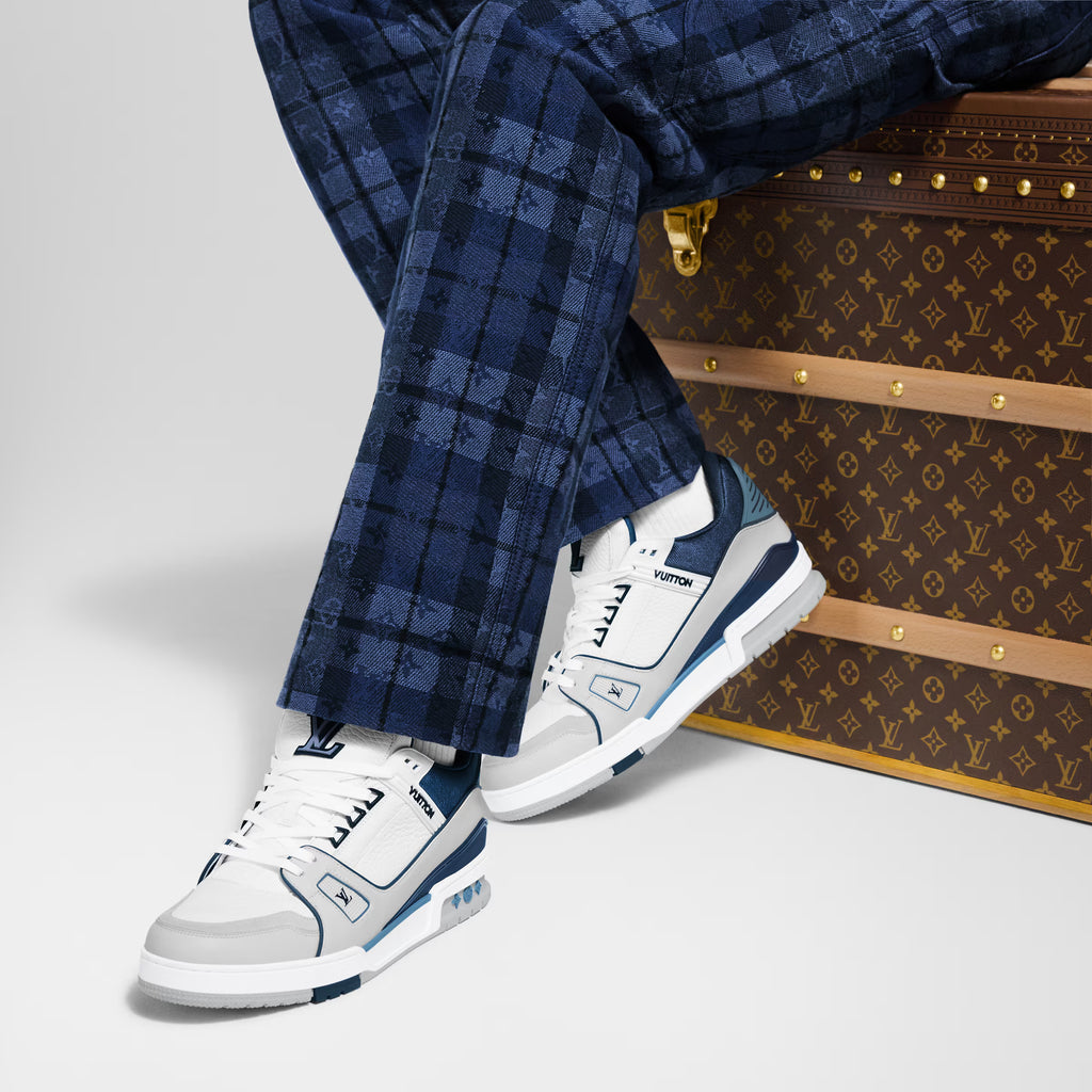White and navy LV trainers on feet with blue plaid trousers