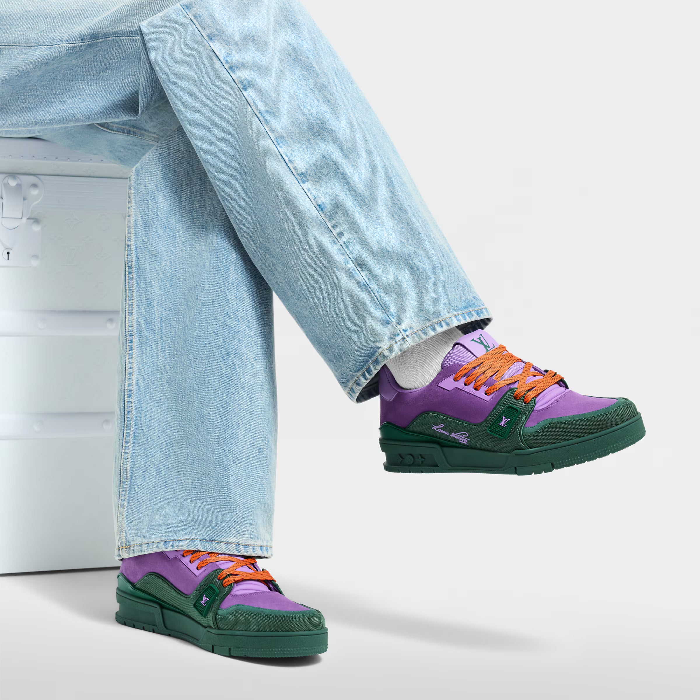 LV Trainer sneakers in purple and green with orange laces worn with light jeans