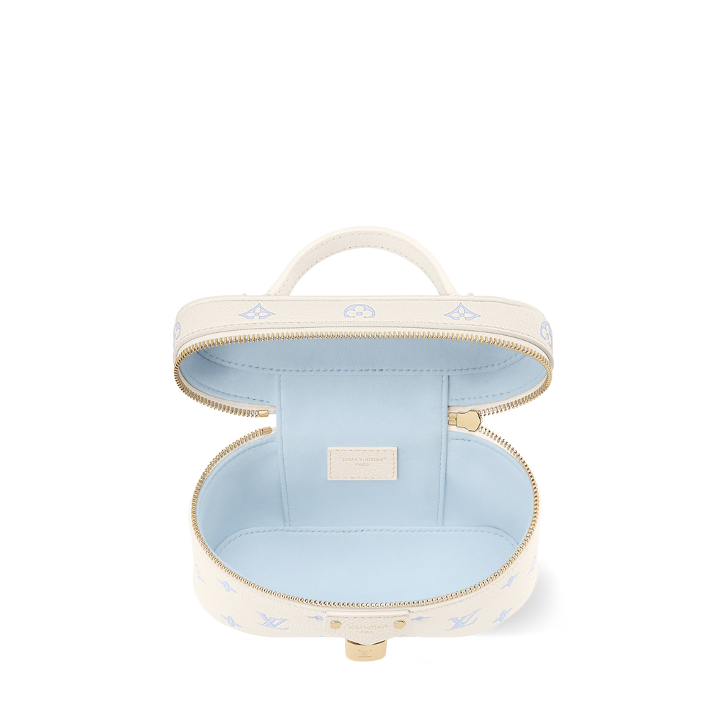 Cream vanity pouch with blue interior, gold zipper, top handle, open round design